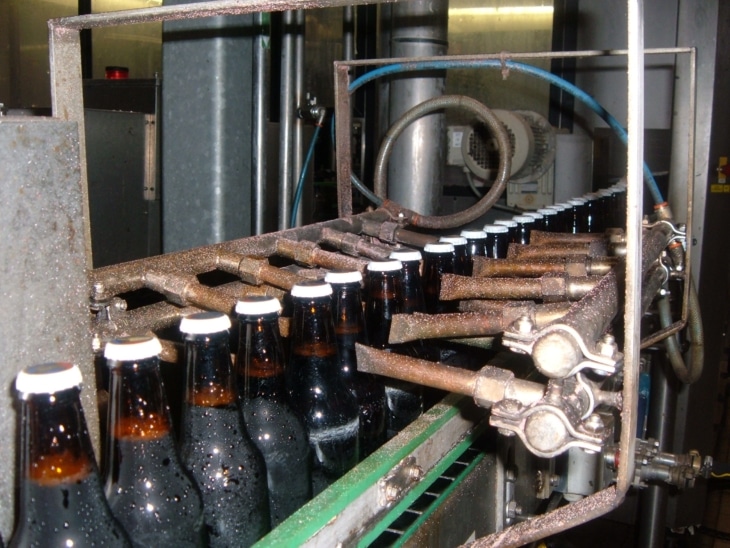 Pinched Copper Pipes Blowing Compressed Air onto bottle on a conveyor belt